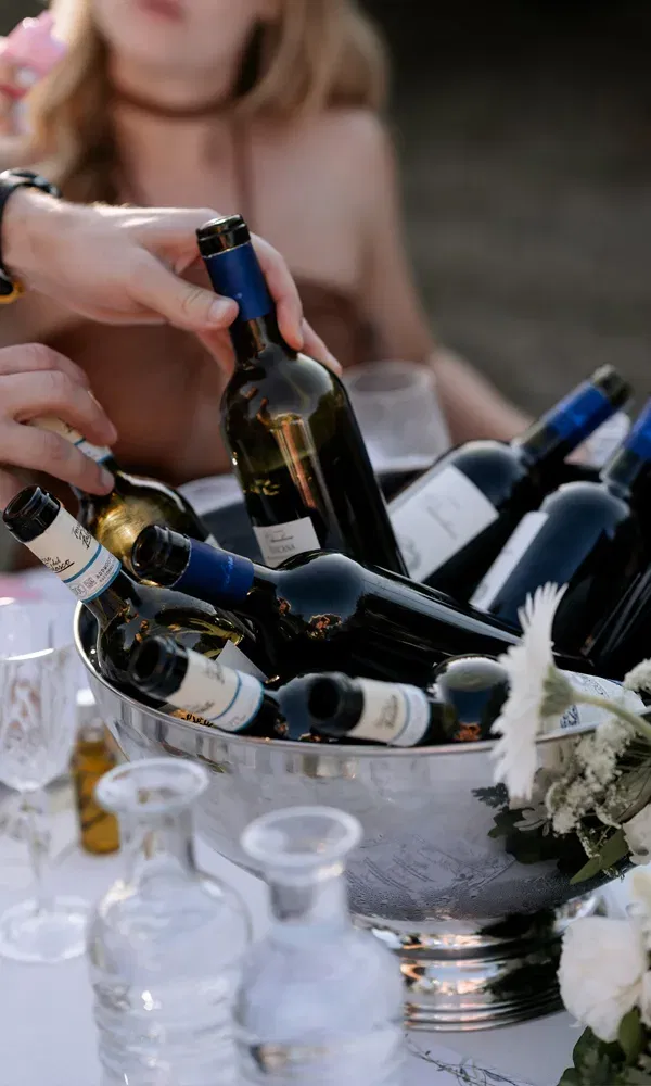 Weinflaschen in einer Eisschale auf dem festlich gedeckten Tisch – ein sommerlicher Genussmoment auf der Hochzeit.