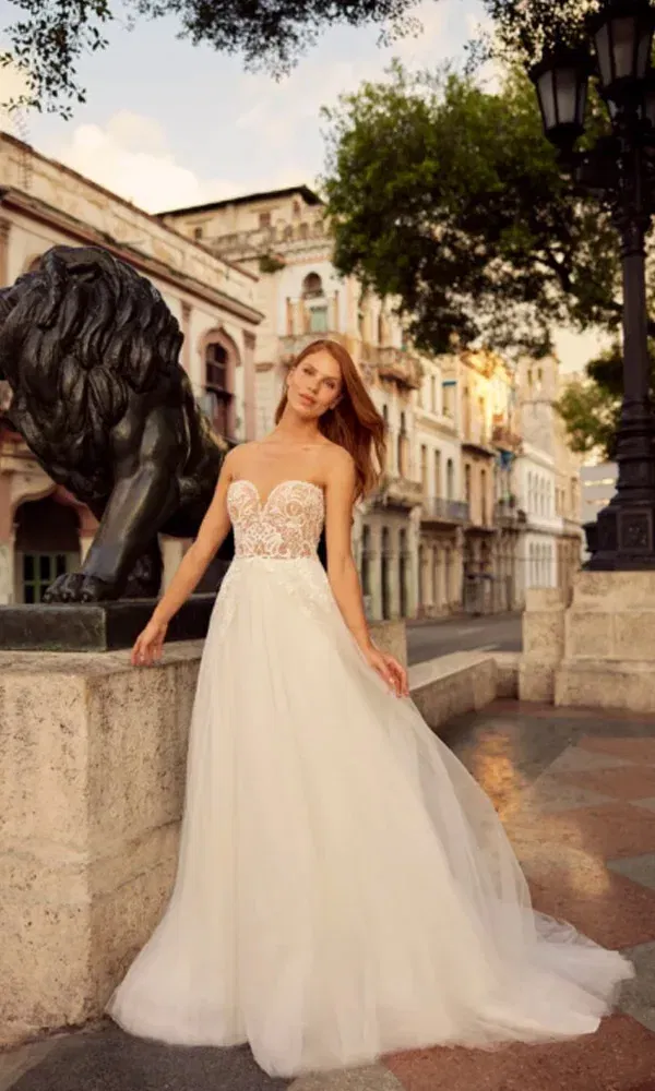 Zarte Eleganz: Eine Braut im soften A-Linien-Kleid steht entspannt in der Stadt und blickt zur Seite.