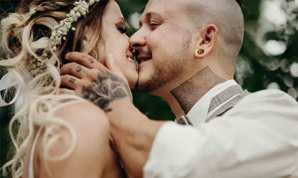 Verliebtes Brautpaar im Nahaufnahme-Porträt, kurz vor einem Kuss, mit zärtlicher Geste und natürlichem Hintergrund.