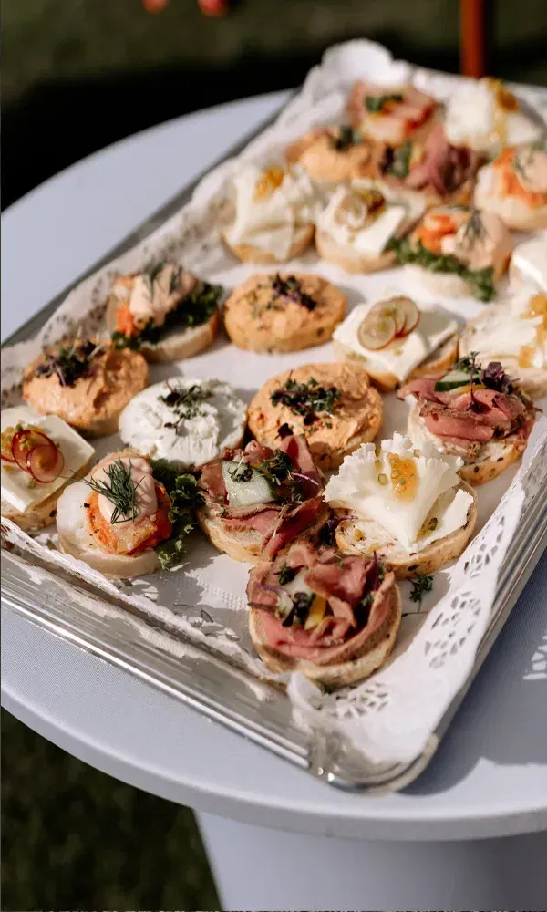 Fein dekorierte Häppchen mit Fisch, Käse und Fleisch auf einem Tablett als Teil des Hochzeitsbuffets im Garten.