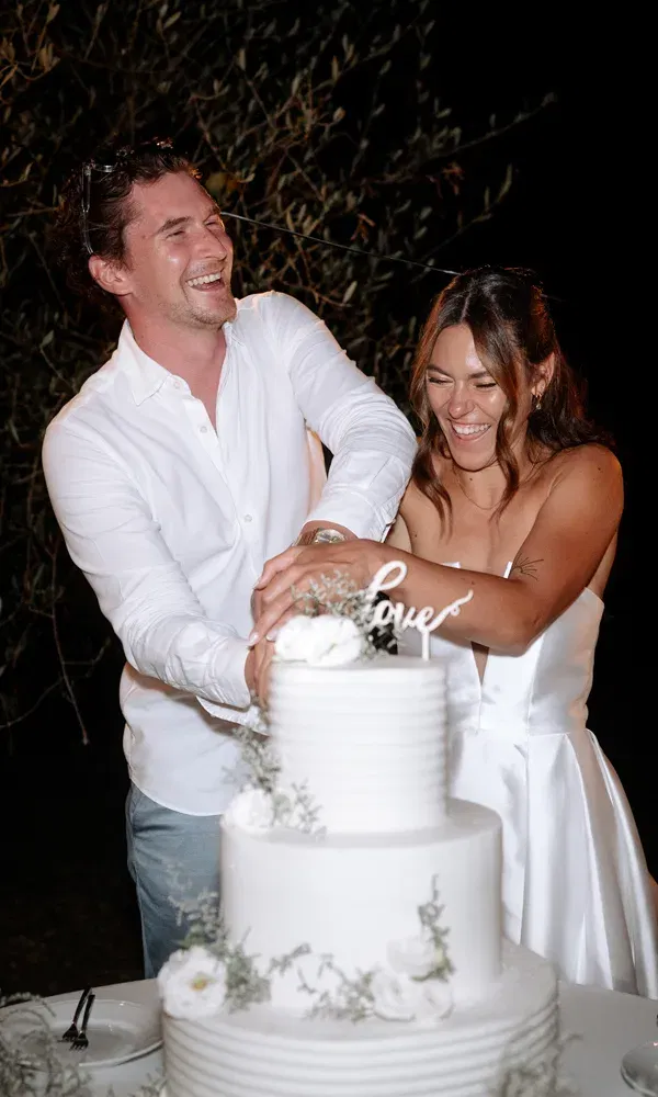 Romantischer Höhepunkt am Abend: Das frisch verheiratete Paar teilt einen ausgelassenen Moment beim Anschneiden der Hochzeitstorte.