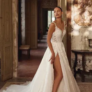 Glitzerndes Spitzenkleid mit hohem Beinschlitz und transparentem Oberteil vor historischen Türen.