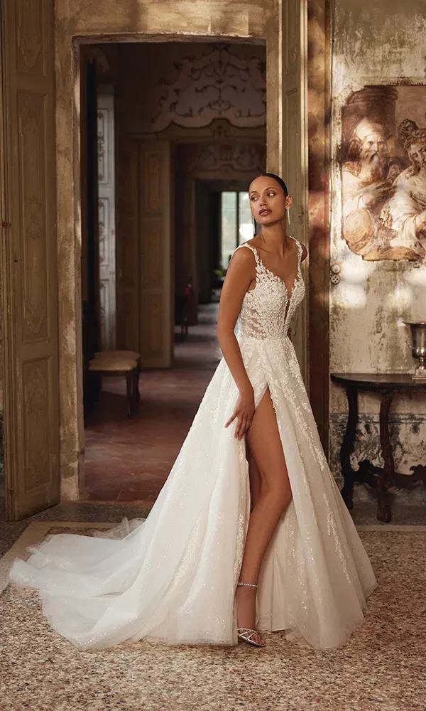 Glitzerndes Spitzenkleid mit hohem Beinschlitz und transparentem Oberteil vor historischen Türen.