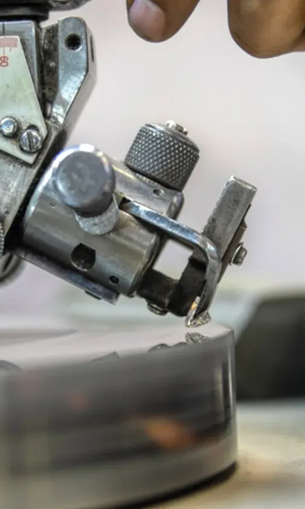 Nahaufnahme einer Maschine beim Schleifen eines Diamanten auf einer rotierenden Scheibe.