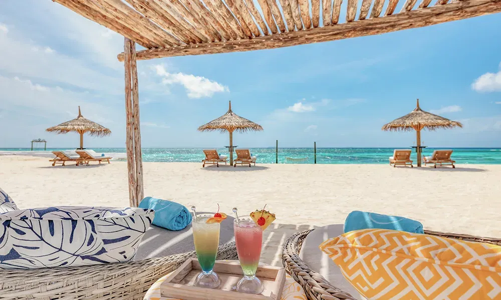 Entspannter Strandtag während der Flitterwochen auf den Malediven – Cocktails unter Palmen im Luxusresort