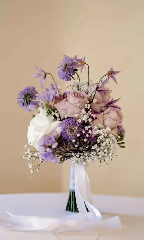 Brautstrauß mit lila und weißen Rosen, kombiniert mit Schleierkraut und gebundenem Satinband