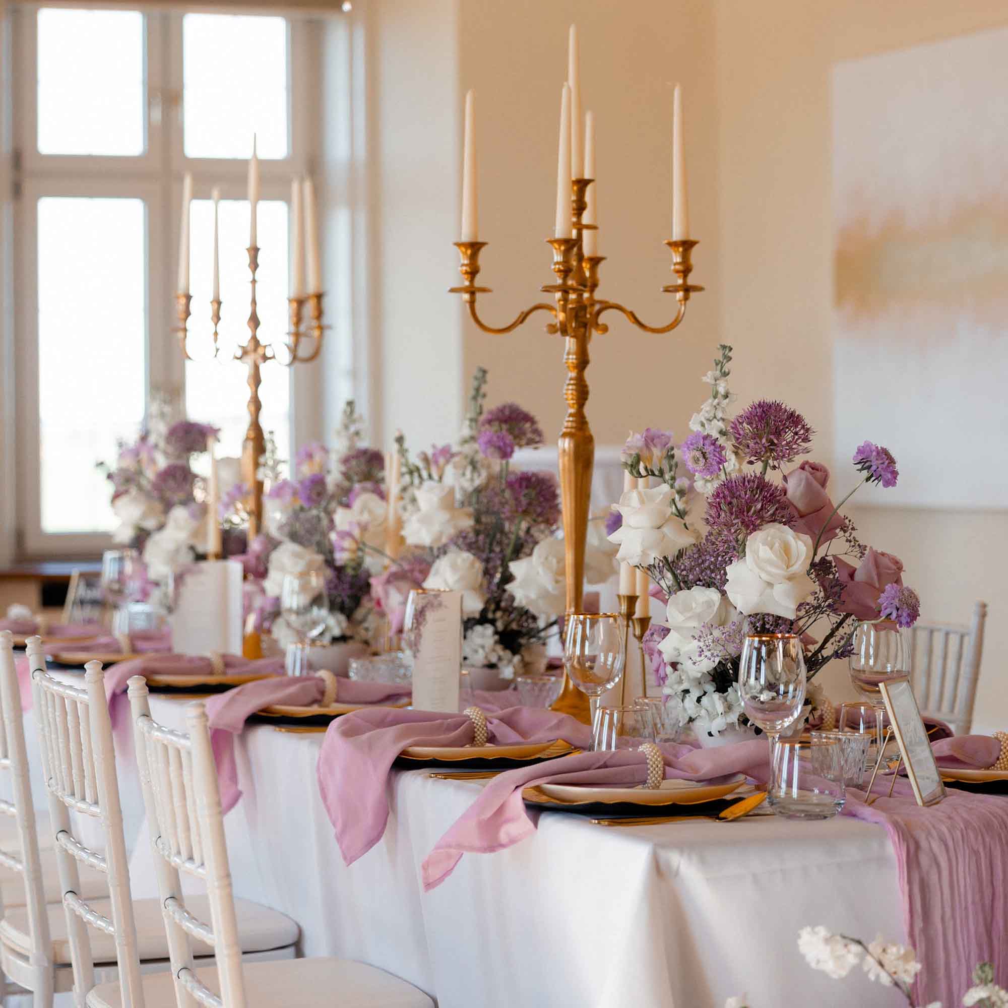 Hochzeitstafel in Lavendel und Gold mit weißen Stühlen, edlem Porzellan und romantischer Floristik