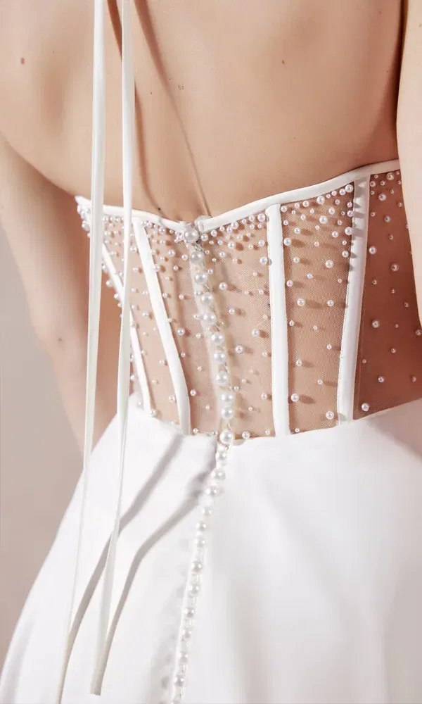Nahaufnahme einer Brautkleid-Rückansicht mit modernem Korsett-Design, perlenbesetztem Tüll und dekorativer Knopfleiste.