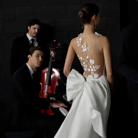 Stilvolle Brautszene: Designerbrautkleid mit floralen Details und Schleife im Rücken, kombiniert mit zeitloser Eleganz.