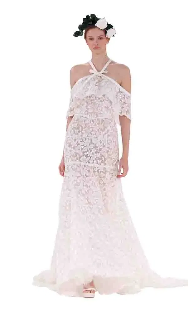 Modernes Spitzenbrautkleid im Bohemian-Stil mit zarten Trägerdetails und romantischem Blumen-Accessoire.