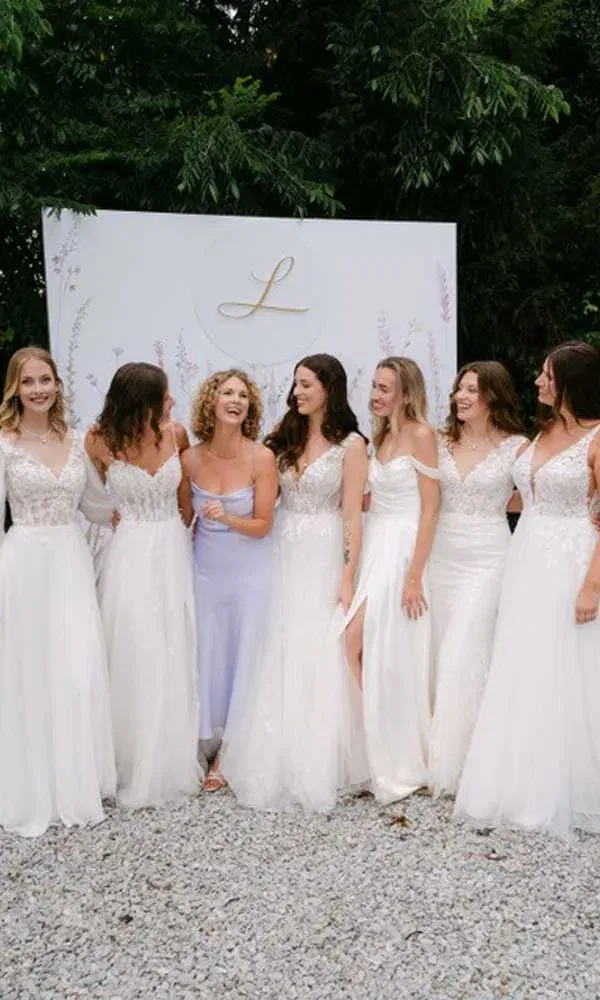 Designerín Sanna Lindström lacht gemeinsam mit sechs Models in weißen Brautkleidern vor dem Logo der Villa Lindström am Niederrhein.