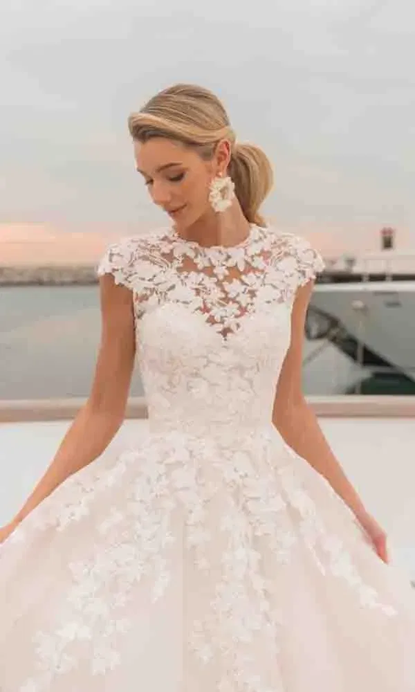 Feminines Hochzeitskleid mit floraler Spitze, transparenter Corsage und romantischem Ballkleid-Rock.