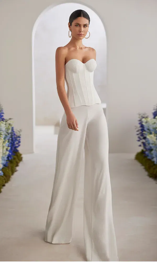 Fashion-forward Brautlook: weißer Jumpsuit mit herzförmigem Bustier und eleganter Silhouette.