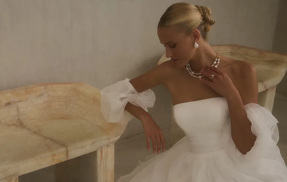 Minimalistisches Brautkleid von Casablanca mit Corsagen-Oberteil, abnehmbaren Tüllärmeln und Perlenkette.