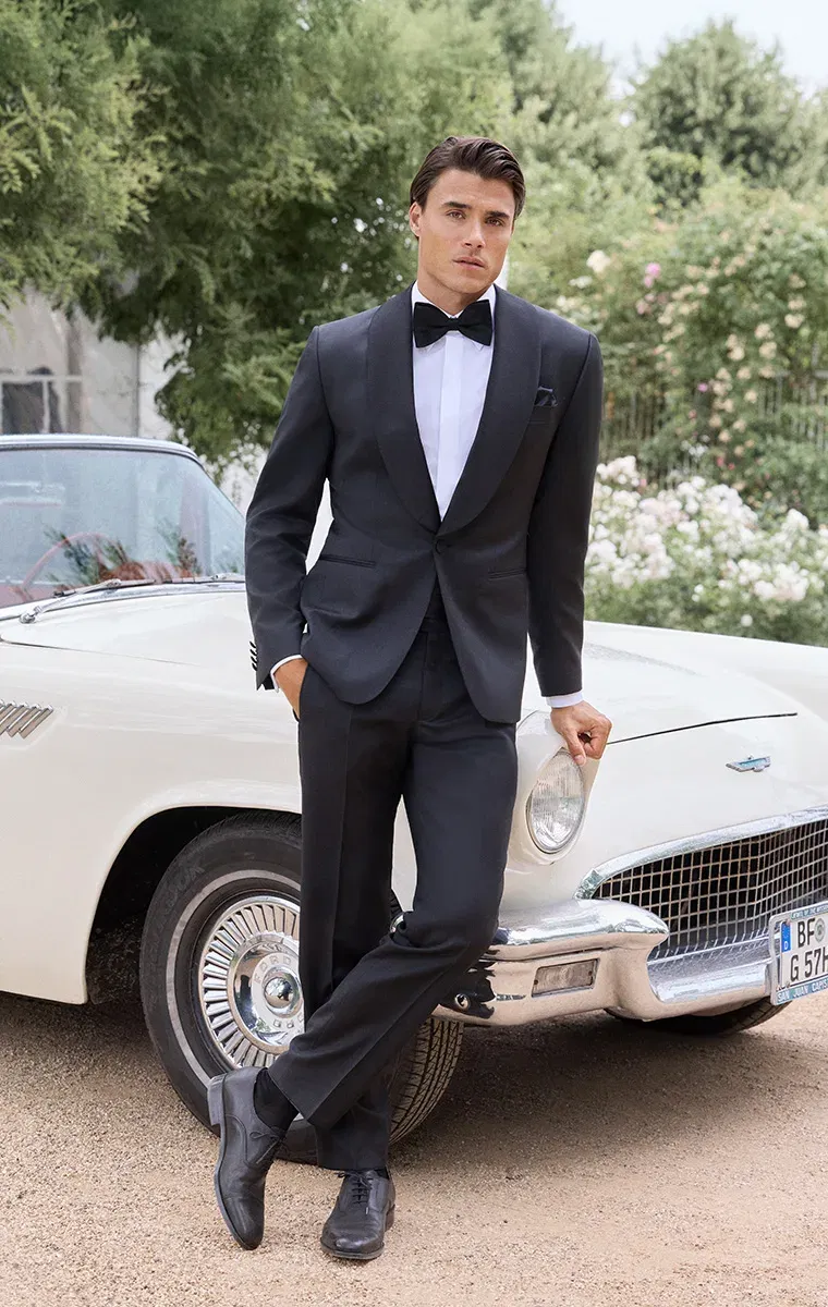 Bräutigam in beerenrotem Doppelreiher-Anzug mit gemusterter Fliege – klassisch-eleganter Hochzeitslook mit modernem Akzent.