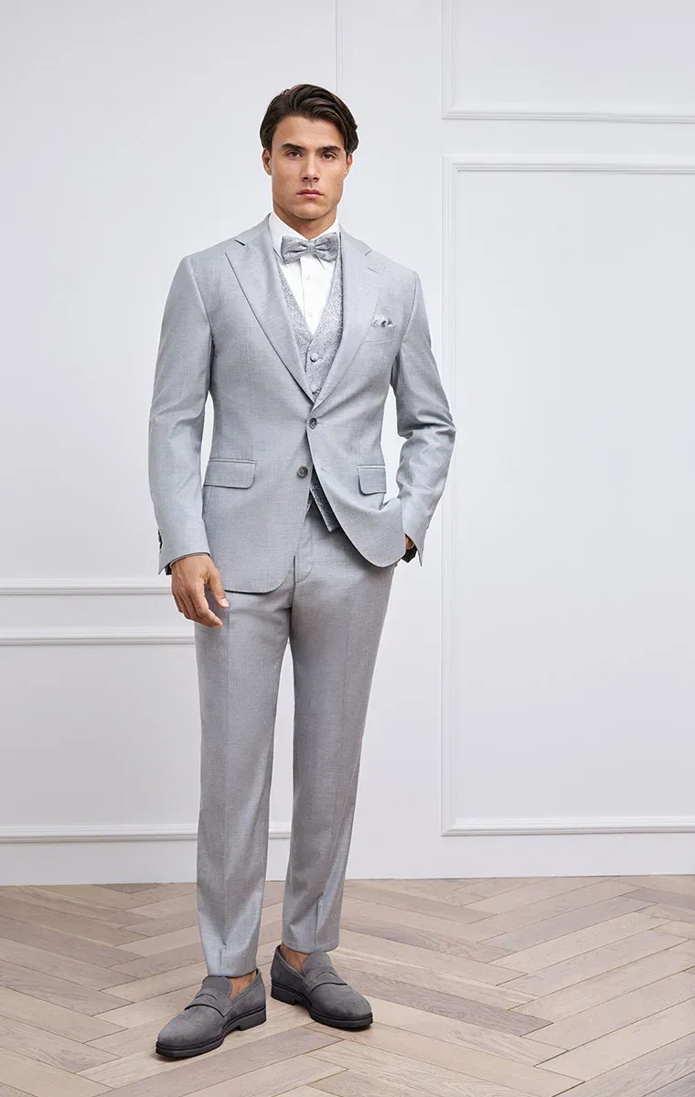 Bräutigam in hellgrauem Hochzeitsanzug mit Weste und Fliege – klassischer Look in modernem Ambiente.