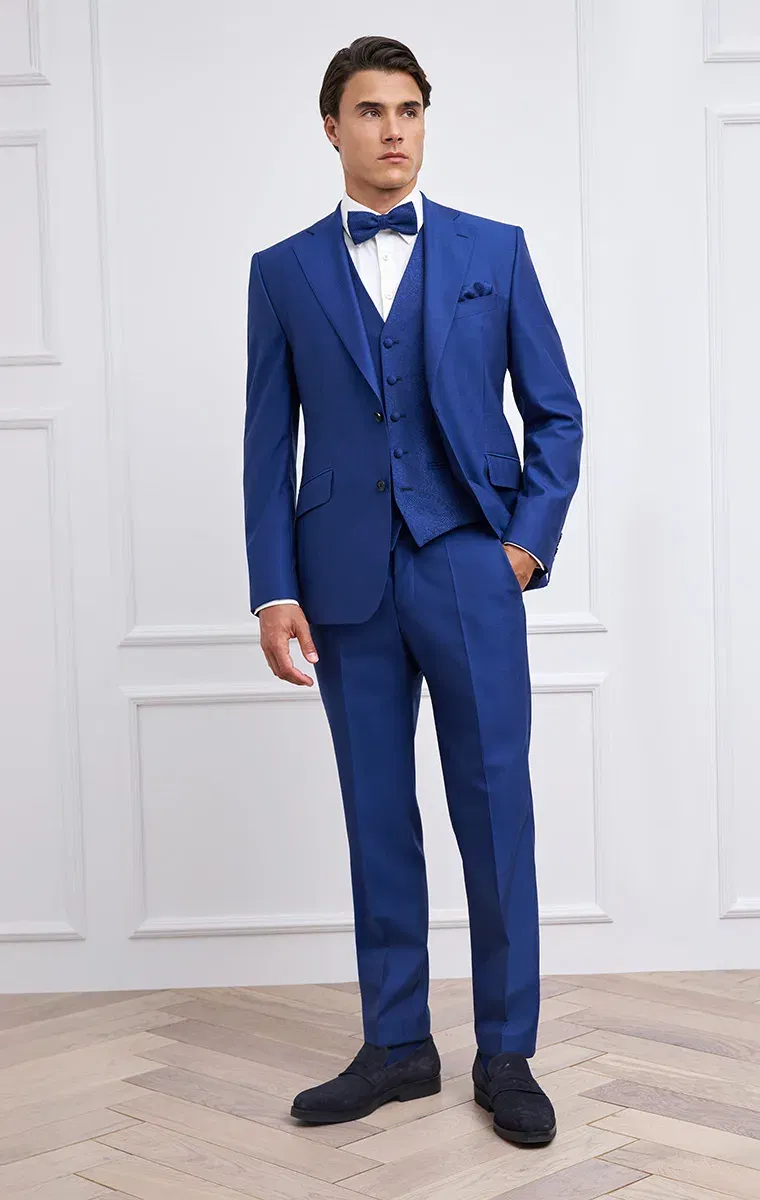 Bräutigam im königsblauen Anzug mit passender Weste und Fliege – eleganter Look für festliche Anlässe.