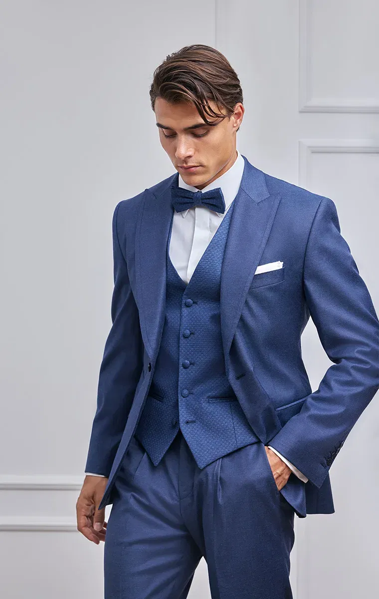 Detailaufnahme eines Bräutigams im dunkelblauen Hochzeitsanzug mit strukturierter Weste und Fliege.