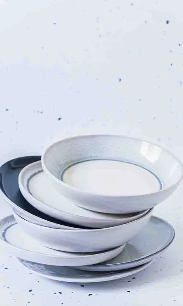 Gestapelte Keramikteller in Blautönen auf hell gesprenkeltem Untergrund.