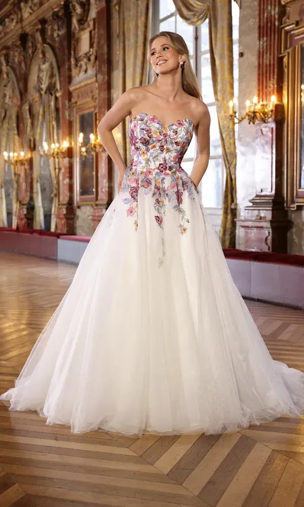 Tülliges Ballkleid mit farbenfrohem, besticktem Oberteil und großem Rock, fotografiert in einem prunkvollen Saal.