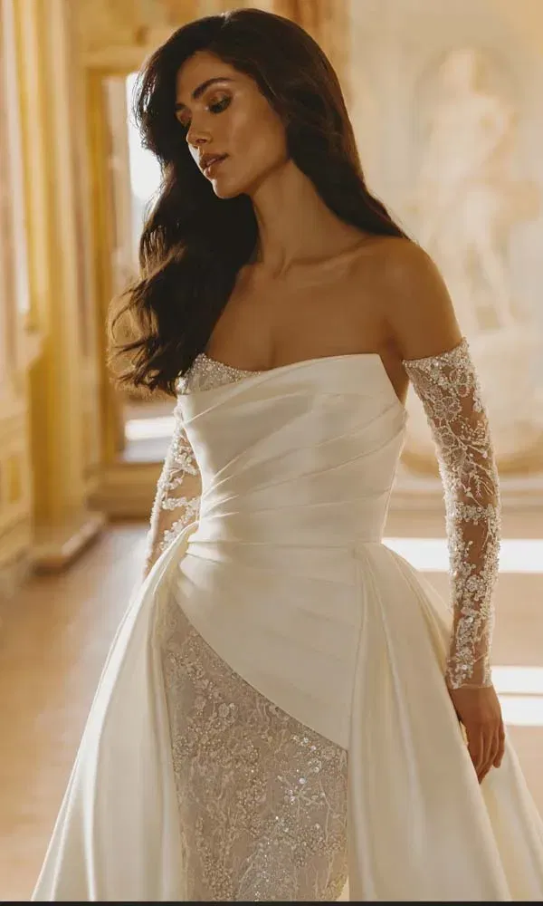 Opulentes Off-Shoulder-Brautkleid mit drapiertem Satin und glitzernder Spitze, fotografiert in einem prunkvollen Raum.