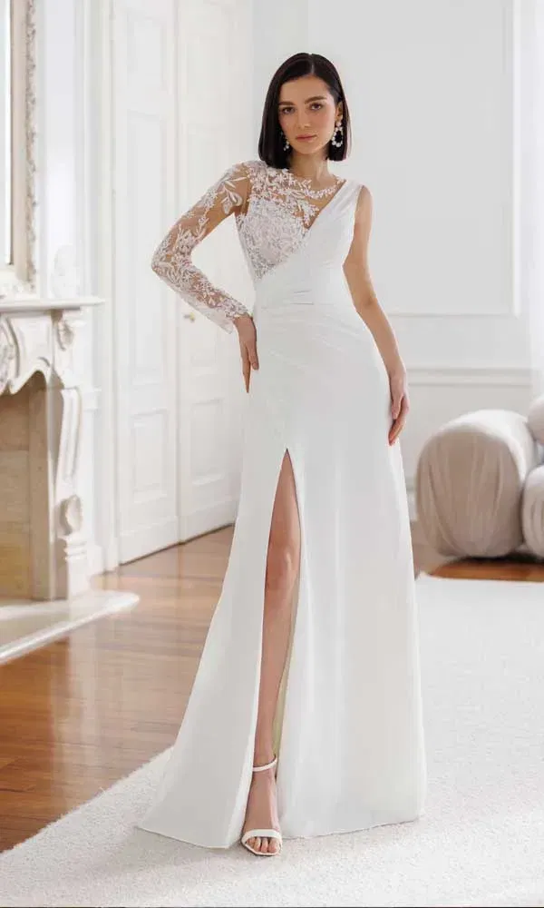 Elegantes Brautkleid mit asymmetrischem Spitzenärmel und hohem Schlitz in heller, klassischer Raumkulisse.