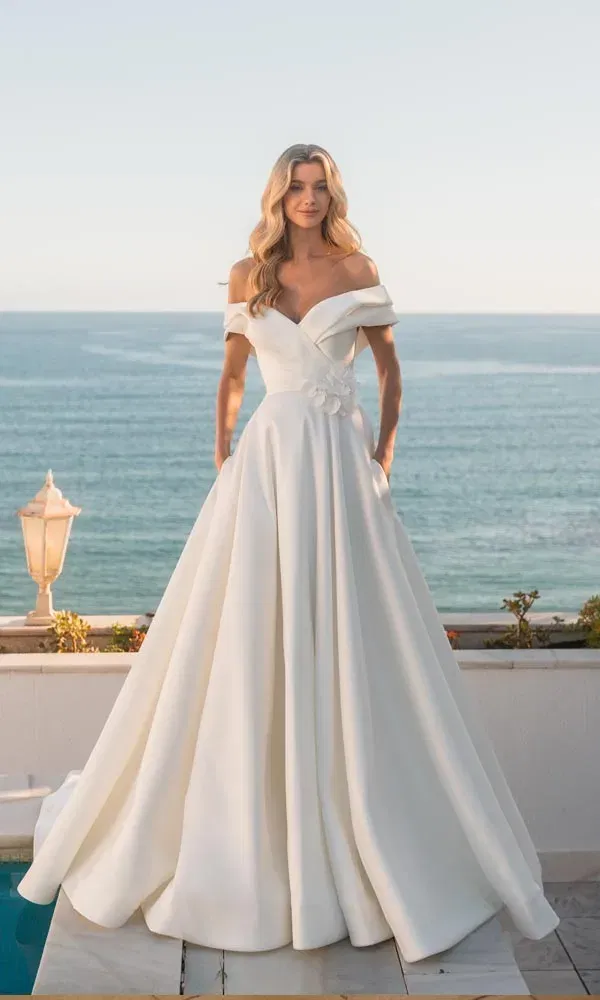 Elegantes Kleid mit schulterfreier Corsage und weitem, fließendem Rock in sonniger Küstenkulisse.