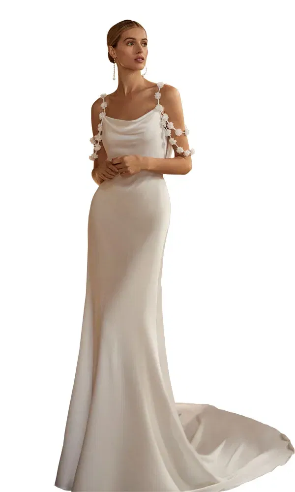 Braut in fließendem Kleid mit Wasserfallausschnitt und zarten Blütenapplikationen an den Armen.