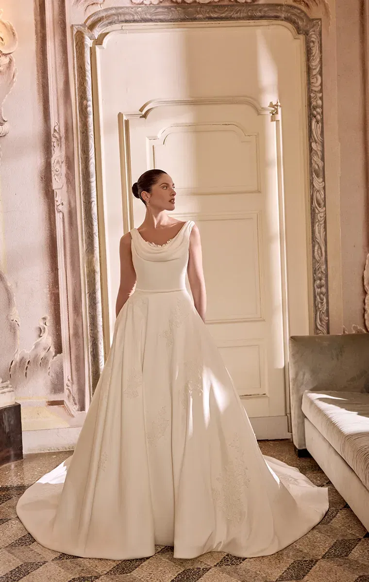 Klassisches A-Linien-Brautkleid mit weich fallendem Drapé-Ausschnitt und floralen Details auf dem Rock.