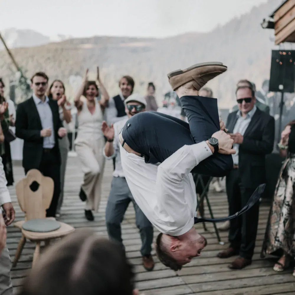 Ein Gast zeigt einen spektakulären Überschlag auf der Tanzfläche, während die Hochzeitsgesellschaft begeistert jubelt.