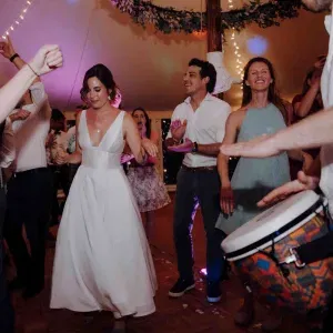 Braut und Gäste feiern ausgelassen auf der Tanzfläche, begleitet von Trommelrhythmen.