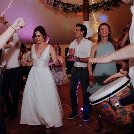 Braut und Gäste feiern ausgelassen auf der Tanzfläche, begleitet von Trommelrhythmen.