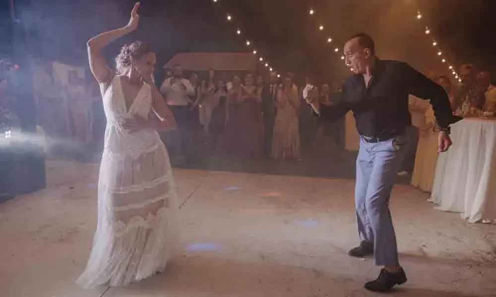 Die Braut tanzt energiegeladen mit einem Gast auf der nächtlichen Tanzfläche, umgeben von Lichterketten und feiernden Gästen.