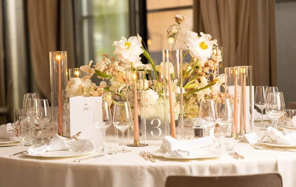 Festlich gedeckter Hochzeitstisch mit eleganter Tischdekoration, zarten Blumenarrangements und Kerzen in warmem Licht im Schlossambiente.