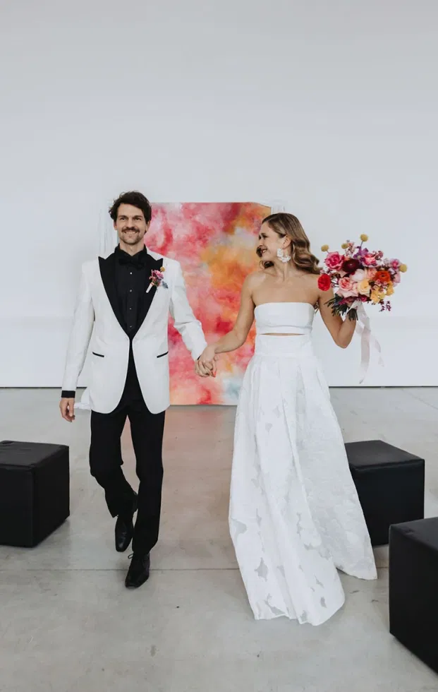 Brautpaar beim Auszug vor abstrakter Leinwand als Trauhintergrund, modernes Artsy Wedding Konzept mit Kunstinstallation.
