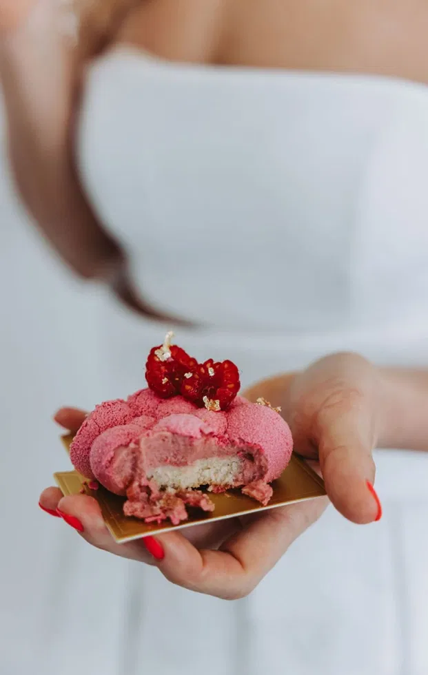 Artsy Wedding Dessert in Pink mit samtiger Oberfläche, Himbeeren und Blattgold, serviert als modernes Hochzeitsdessert.