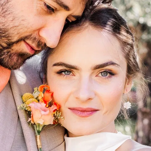 Intimes Brautpaar-Porträt mit orangefarbener Boutonnière – natürliches Tageslicht bei der Gartenhochzeit