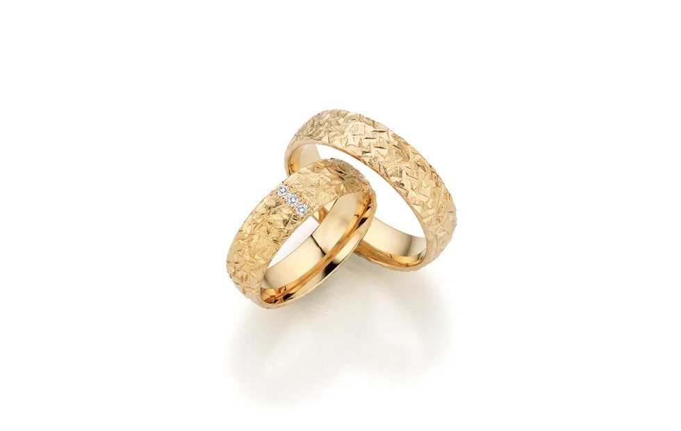 Strukturierte Fischer Trauringe aus Gelbgold mit geometrischer Oberfläche und Diamantbesatz im Damenring.