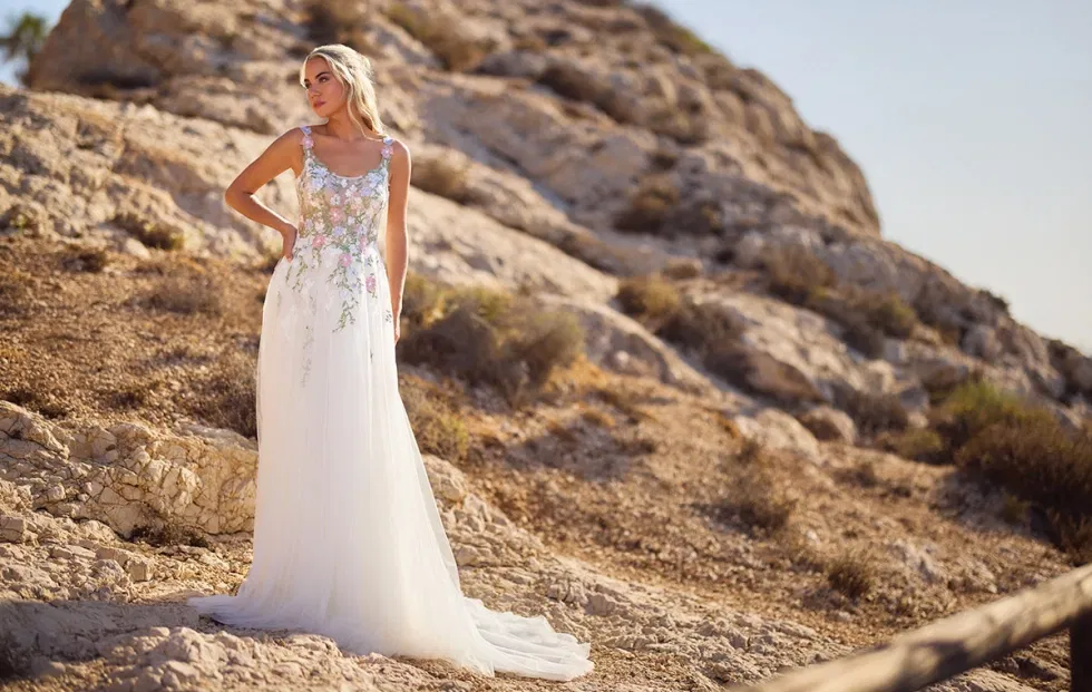 Brautkleid mit zartem, floralen Spitzenmuster und leichtem Tüllrock, fotografiert in einer felsigen Naturkulisse bei warmem Tageslicht.