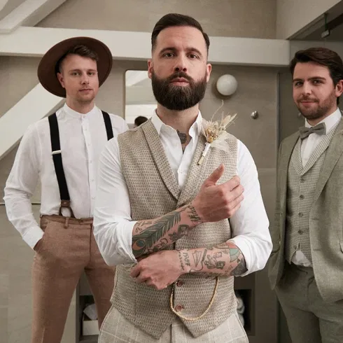 Bräutigam mit Trauzeugen in abgestimmten Anzügen kurz vor der Hochzeit, selbstbewusst und ruhig, bereit für den großen Tag.