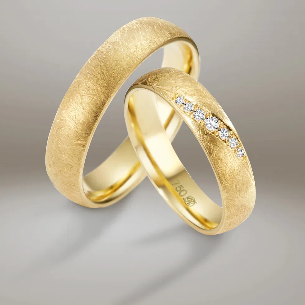 Gehämmerte Trauringe aus Gelbgold mit Diamantreihe – elegante Eheringe im modernen Design.