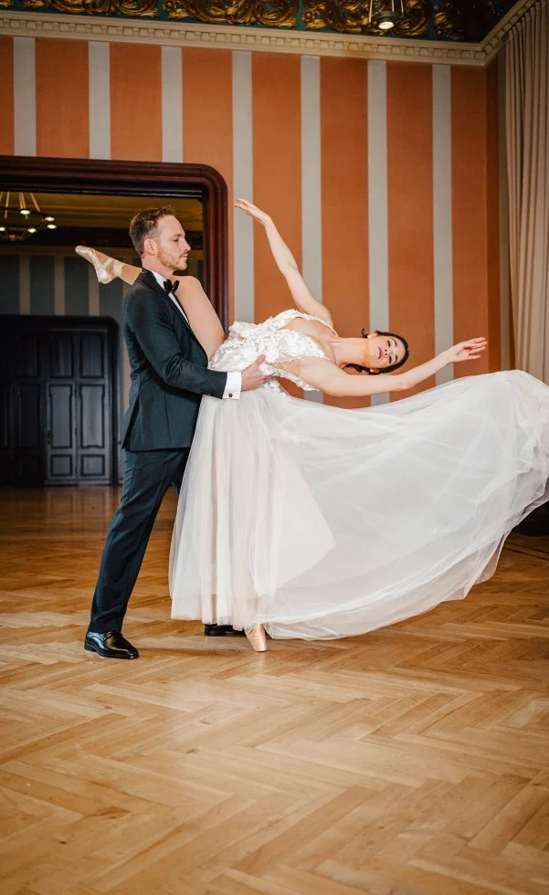 Brautpaar im eleganten Saal beim Tanz, der Bräutigam hält die Braut in einer anmutigen Pose, während ihr Tüllkleid weich über den Boden fließt.