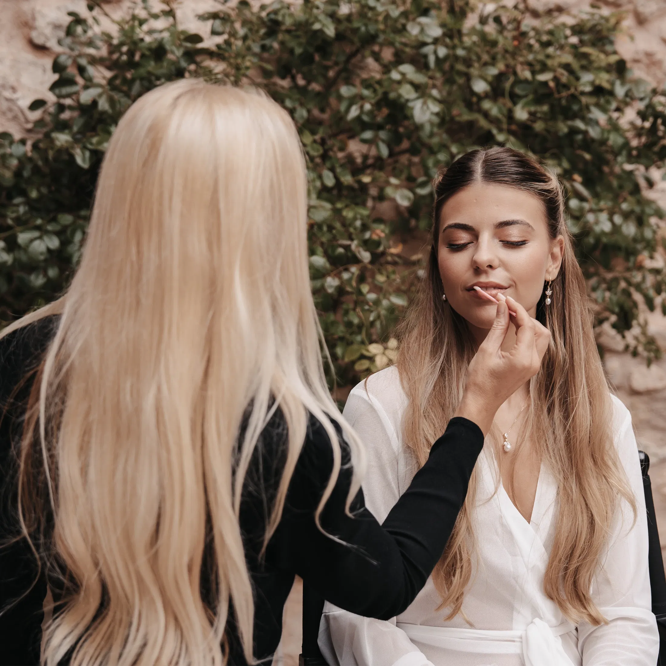 Make-up-Artistin trägt einer Braut beim Getting Ready Lippenstift auf – ein natürlicher Brautlook entsteht.