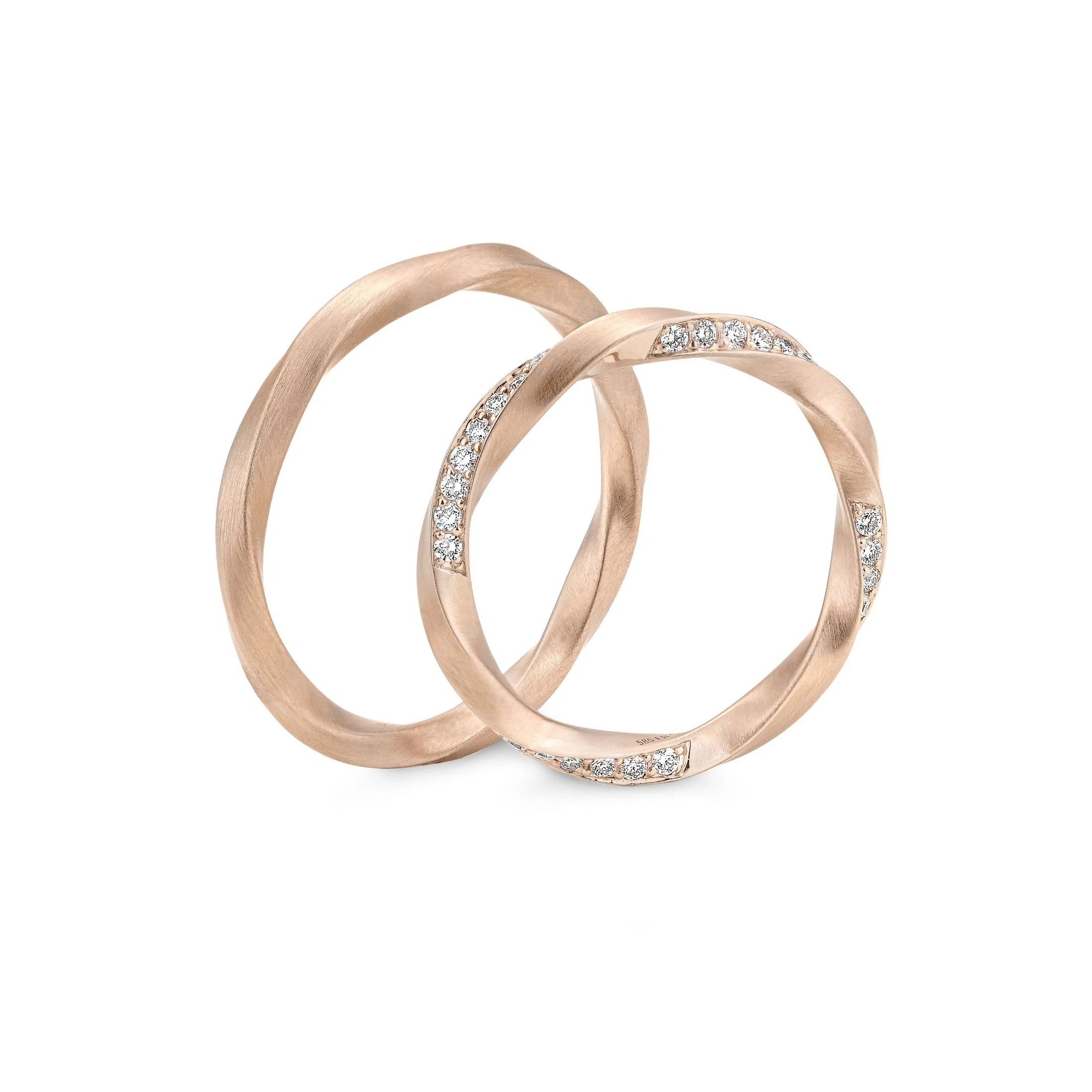 Zarte Eheringe in Roségold mit sanft gedrehter Form und seitlich eingefassten Diamanten.