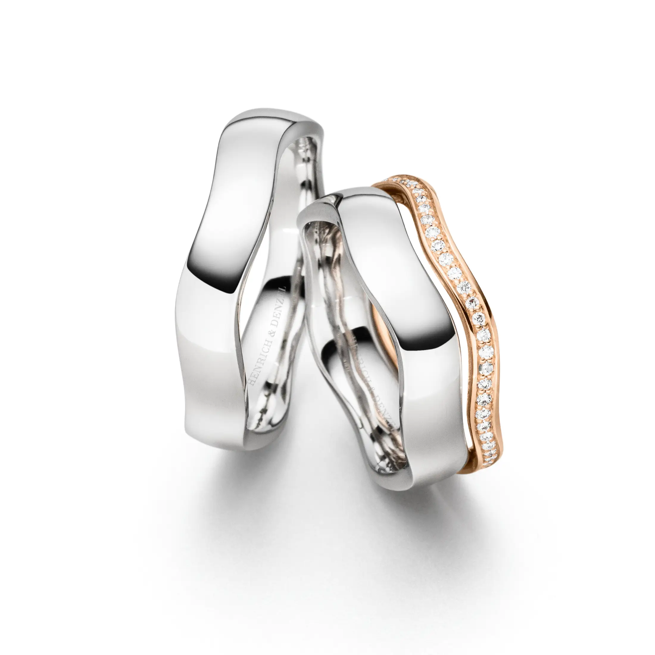 Außergewöhnliche Trauringe aus Weißgold und Roségold mit asymmetrischer Form und funkelnden Diamanten.