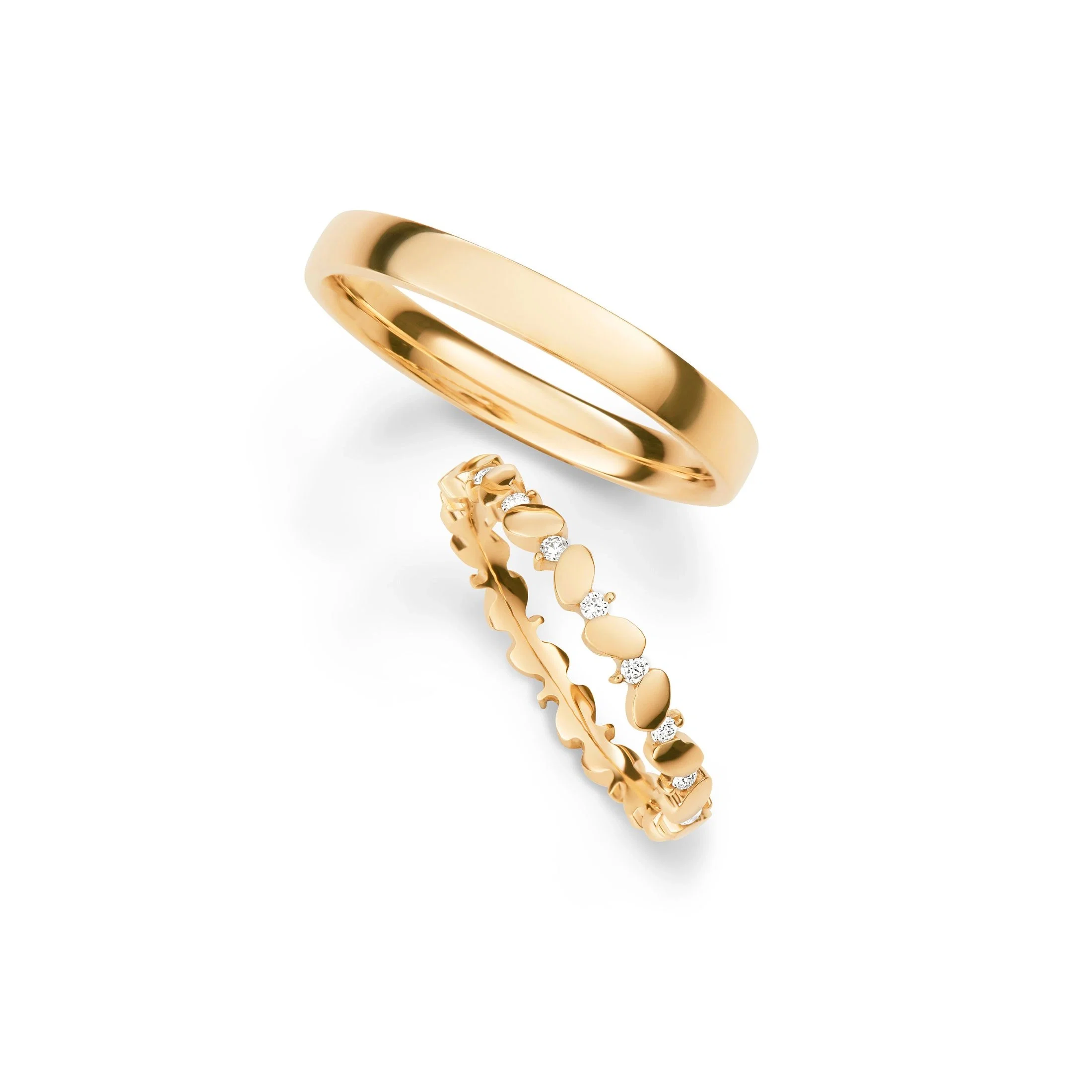 Minimalistische Eheringe aus Gelbgold kombiniert mit kreativem Diamantring in floralem Design.