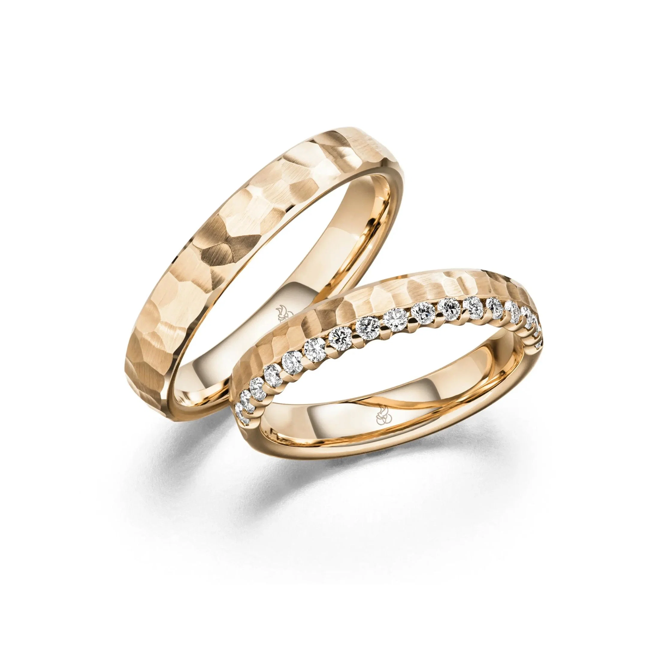 Strukturierte Trauringe aus Roségold mit gehämmerter Oberfläche und funkelnder Diamantreihe.