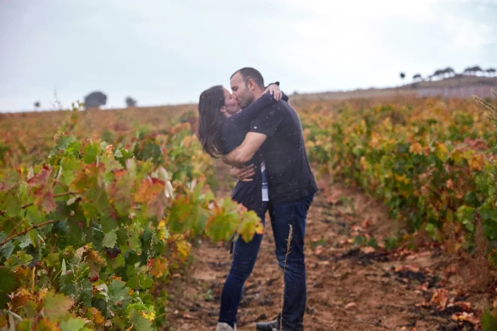 Verliebtes Paar küsst sich innig zwischen herbstlichen Weinreben bei einem romantischen Outdoor-Couple-Shooting.