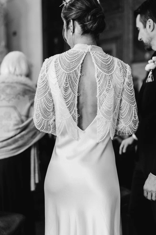 Braut-Aufnahme von hinten, man sieht die elegante perlenbesetzte Bluse. Das Kleid hat einen V-Rückenausschnitt