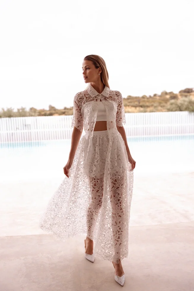 Dieses romantische Ensemble aus der Destination Romance-Kollektion von Demetrios besteht aus einem Bandeau-Top und Shorts, kombiniert mit einer Spitzenbluse und einem Überrock.